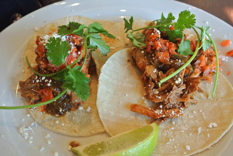 Cochinita de Pibil: Pork slow braised in Banana Leaves and Chiles, Tomatillo-Chipotle Salsa, Escabeche, Queso Fresco, Cilantro
